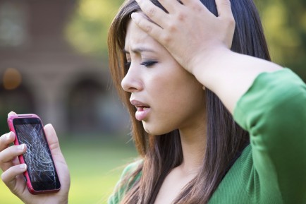 Mixed race woman with shattered cell phone